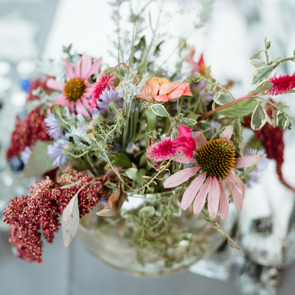 arm holding a bouquet of flowers wrapped in brown paper